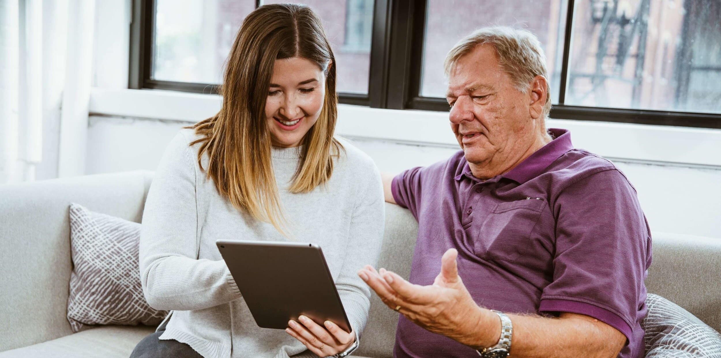 Daughter teaching her father how to use a tablet