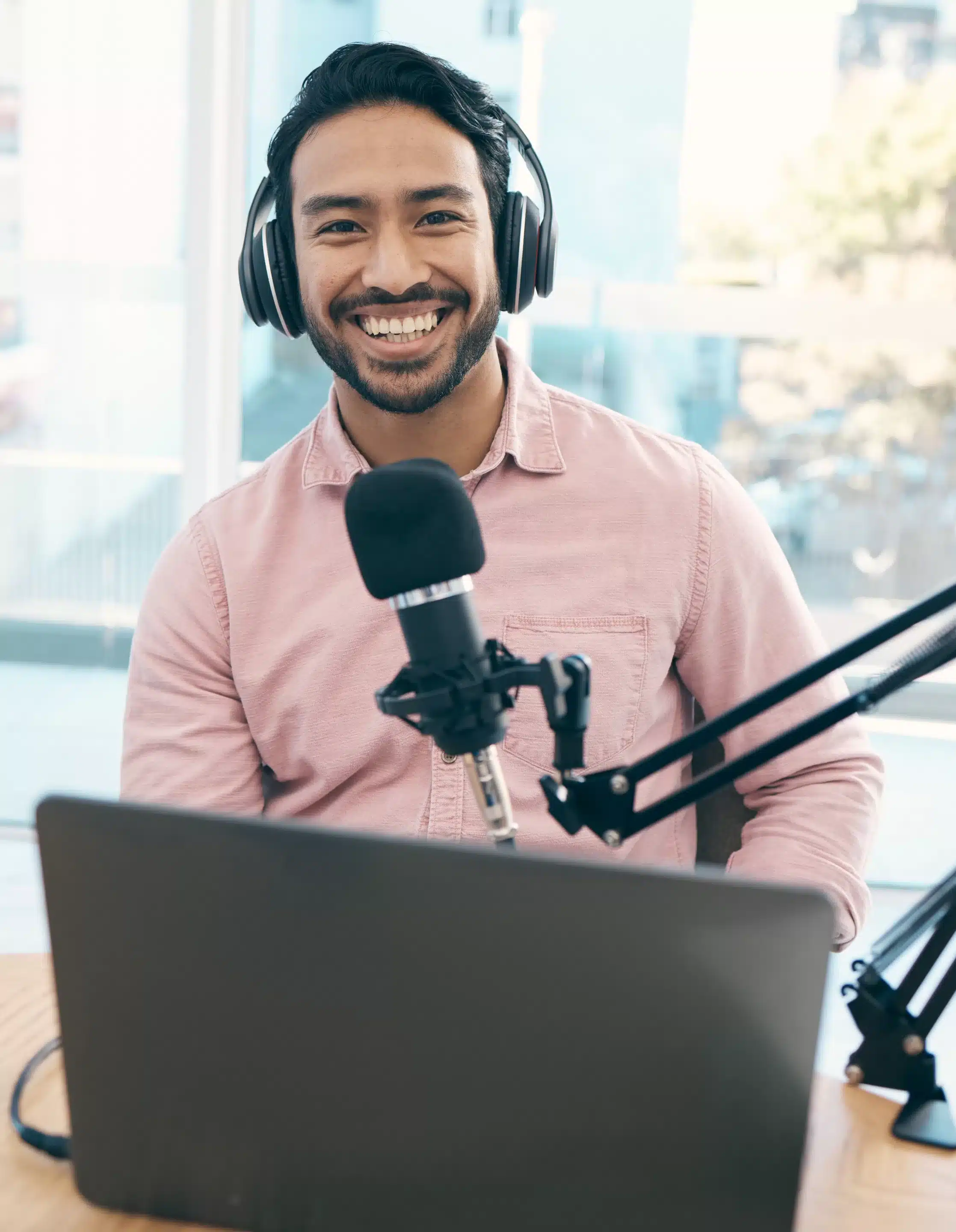 A man wearing headphones and smiling at the camera